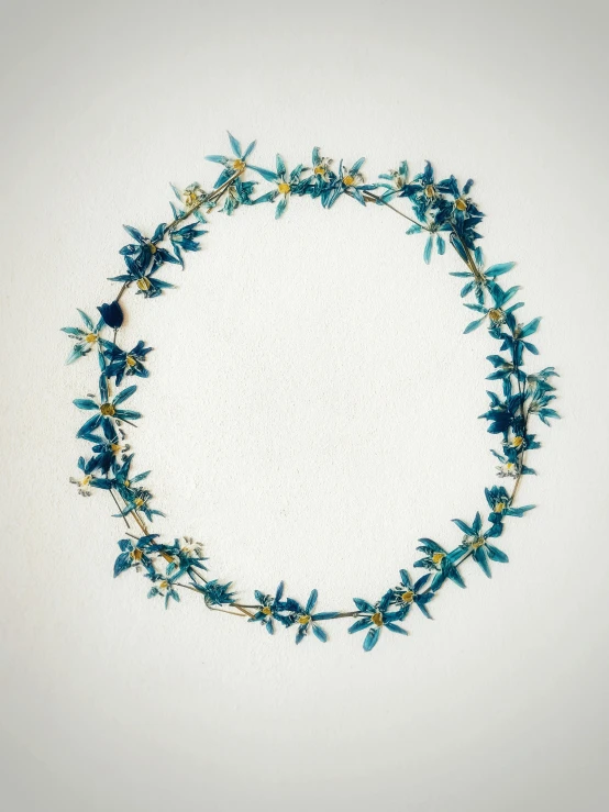 a wreath of blue flowers on a white background, by Helen Stevenson, land art, 14k gold wire, 1990s photograph, copper and deep teal mood, aerial view. hand stitching