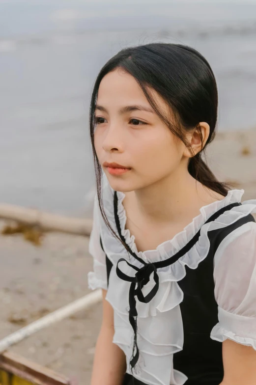 a woman sitting on a bench next to a body of water, an album cover, inspired by Tang Yifen, unsplash, shin hanga, 🤤 girl portrait, collar on neck, frill, white and black
