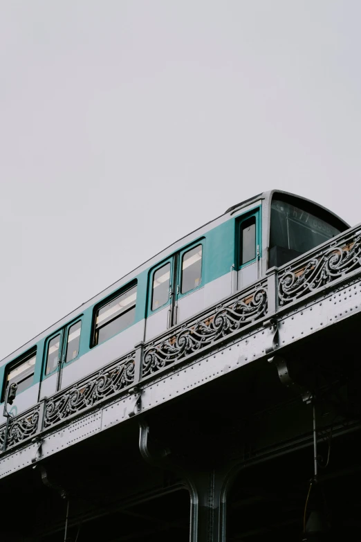 a train traveling over a bridge on a cloudy day, unsplash, art nouveau, white and teal metallic accents, gif, paris, market