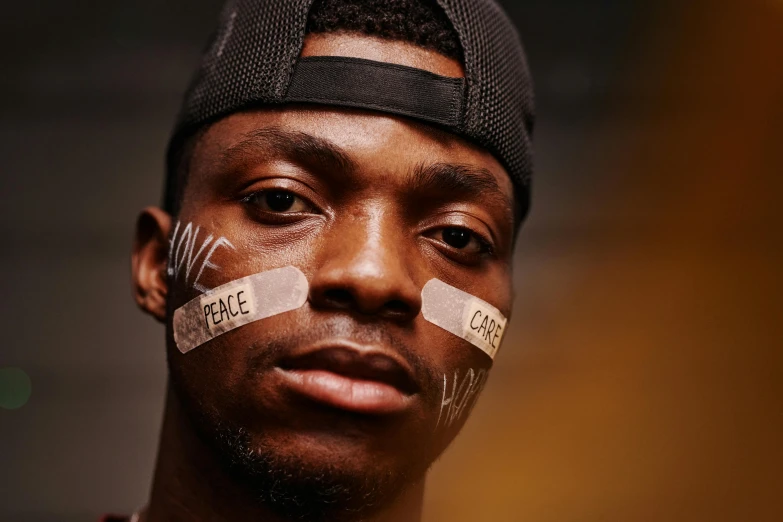 a close up of a person with tape on their face, by Stokely Webster, trending on pexels, graffiti, man is with black skin, jaylen brown, proud looking, press shot