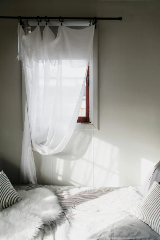 a bed sitting in a bedroom next to a window, inspired by Elsa Bleda, unsplash, light and space, white cloth in wind shining, taken in the late 2010s, curtain, beds