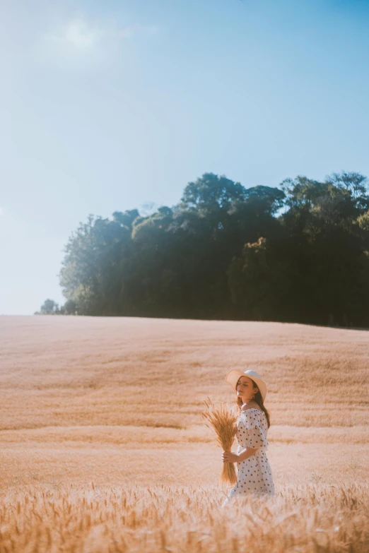 a woman standing in a field of wheat, inspired by Russell Drysdale, unsplash, medium format. soft light, vsco, near forest, italy