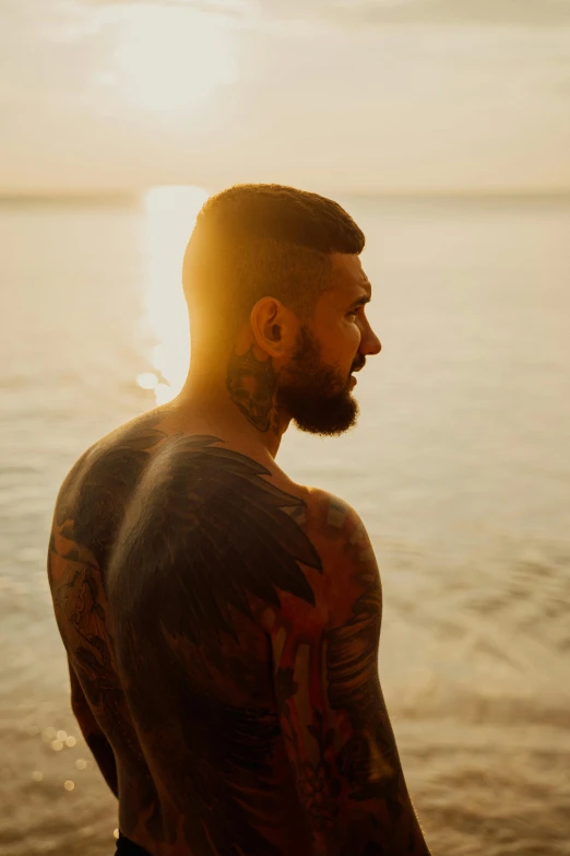 a man standing in front of a body of water, a tattoo, profile image, morning glow, tattooed skin, slide show