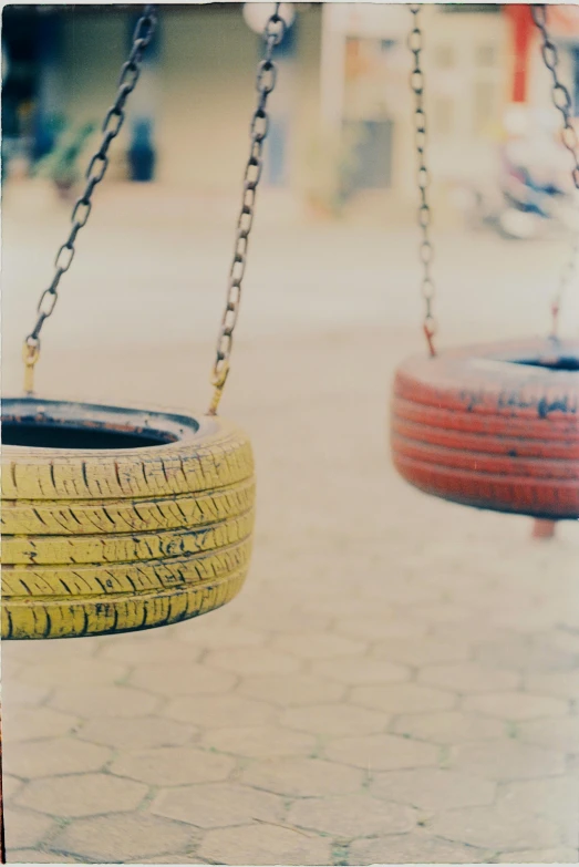 a couple of tires hanging from a chain, a colorized photo, unsplash, postminimalism, playground, vsco film grain, yellowed with age, made of rubber