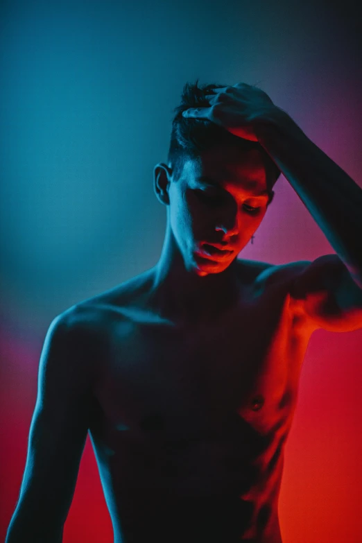 a man standing in front of a red and blue background, trending on pexels, bisexual lighting, photo of a model, androgyny, lit up in a dark room