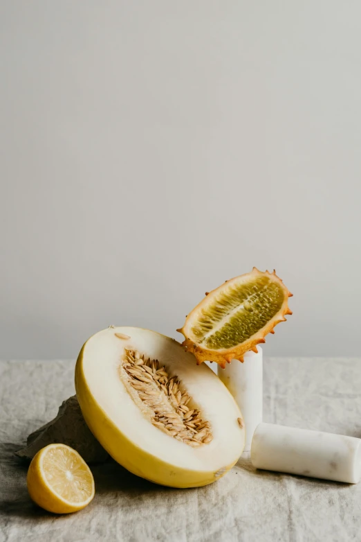 a close up of a sliced melon on a table, a still life, unsplash, baroque, full body image, white, yellow, grey