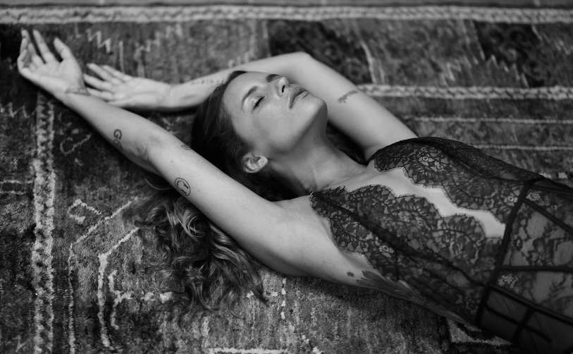 a black and white photo of a woman laying on a rug, by Kristian Zahrtmann, pexels, renaissance, wearing shipibo tattoos, wings lace wear, concept photoset, sunbathed skin