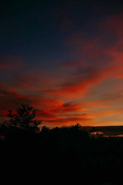 a sunset view from the top of a hill, by Robbie Trevino, red colors, low quality photo, dynamic sky, cinematic shot ar 9:16 -n 6 -g