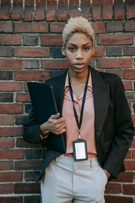 a woman standing in front of a brick wall, security agent, photo of a black woman, androgynous person, holding a clipboard