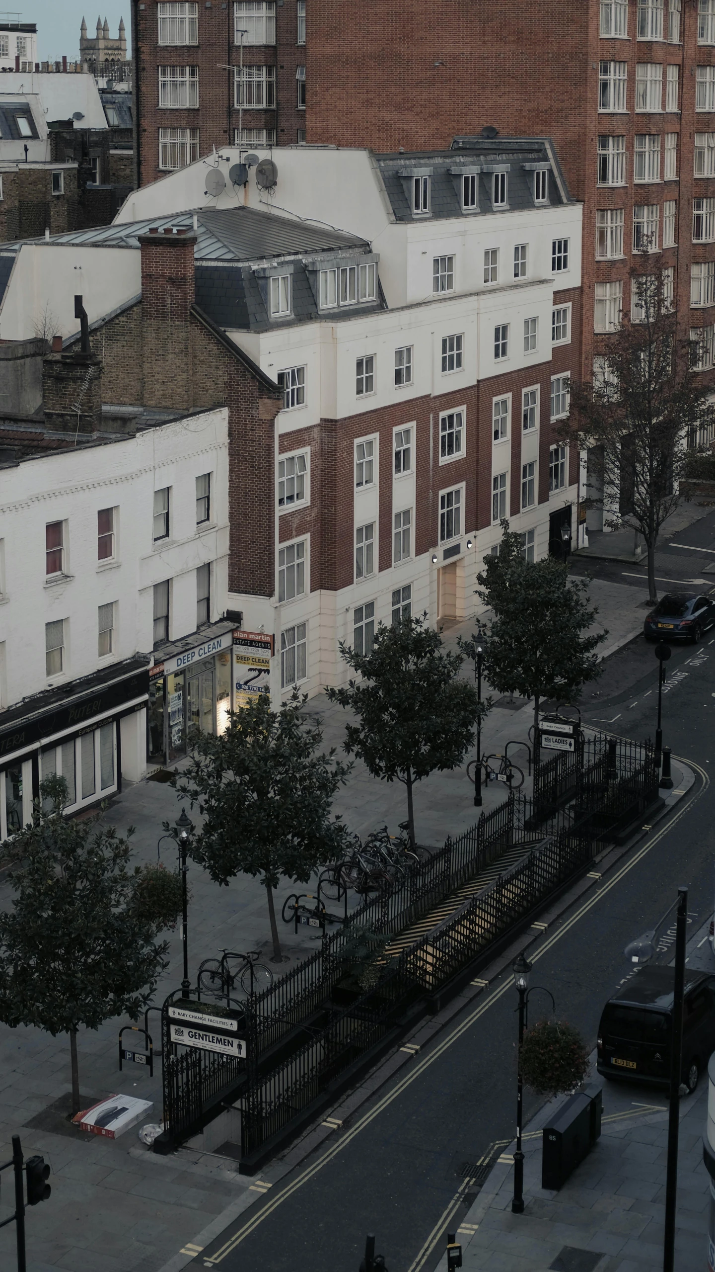 a city street filled with lots of traffic next to tall buildings, unsplash, barnet, low quality photo, early evening, aerial footage