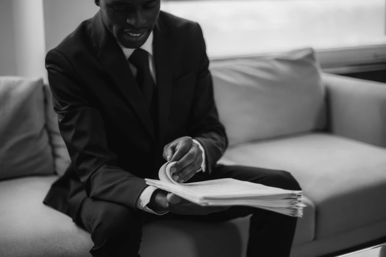 a man in a suit sitting on a couch, by Daniel Gelon, pexels contest winner, signing a bill, sharp black skin, stacked image, black paper