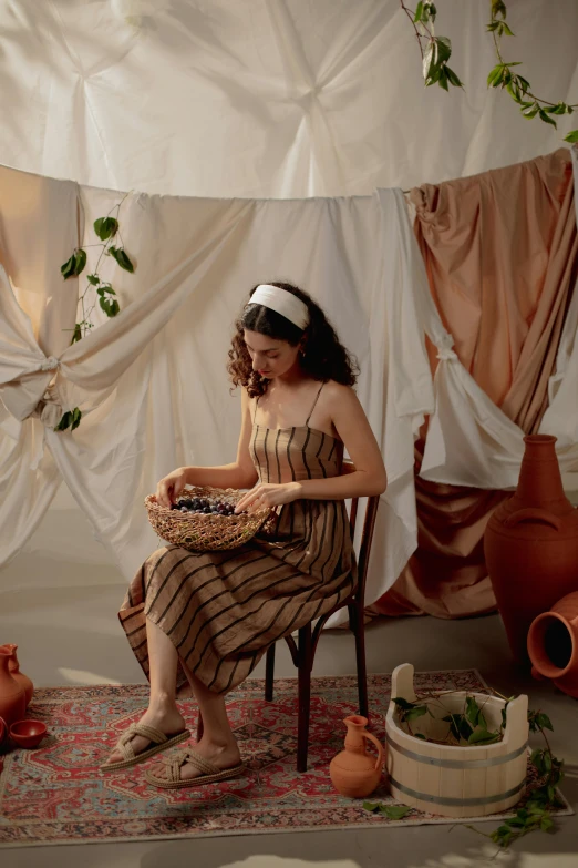 a woman sitting in a chair holding a basket, trending on pexels, renaissance, soft silk dress, clay, indoor scene, arab inspired