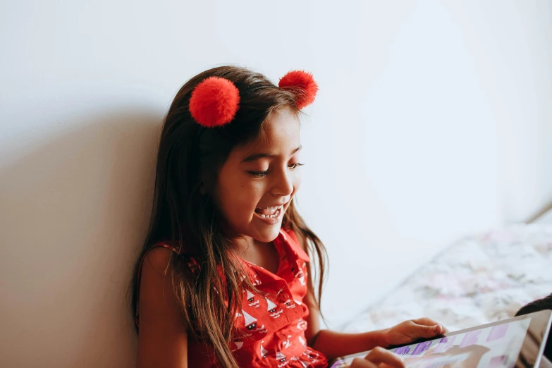 a little girl sitting on a bed with a laptop, pexels contest winner, incoherents, wearing a red outfit, from reading to playing games, cute ears, earing a shirt laughing