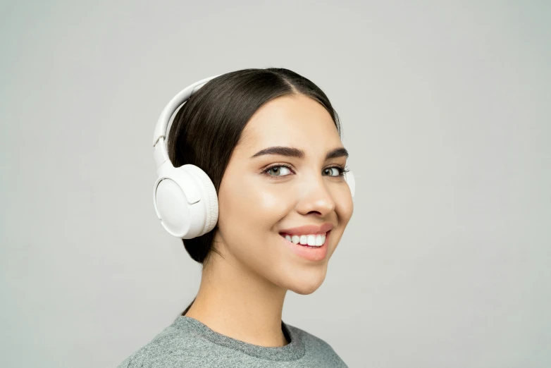 a woman wearing headphones and smiling at the camera, trending on pexels, hurufiyya, white finish, detailed product image, on a gray background, integrated synthetic android