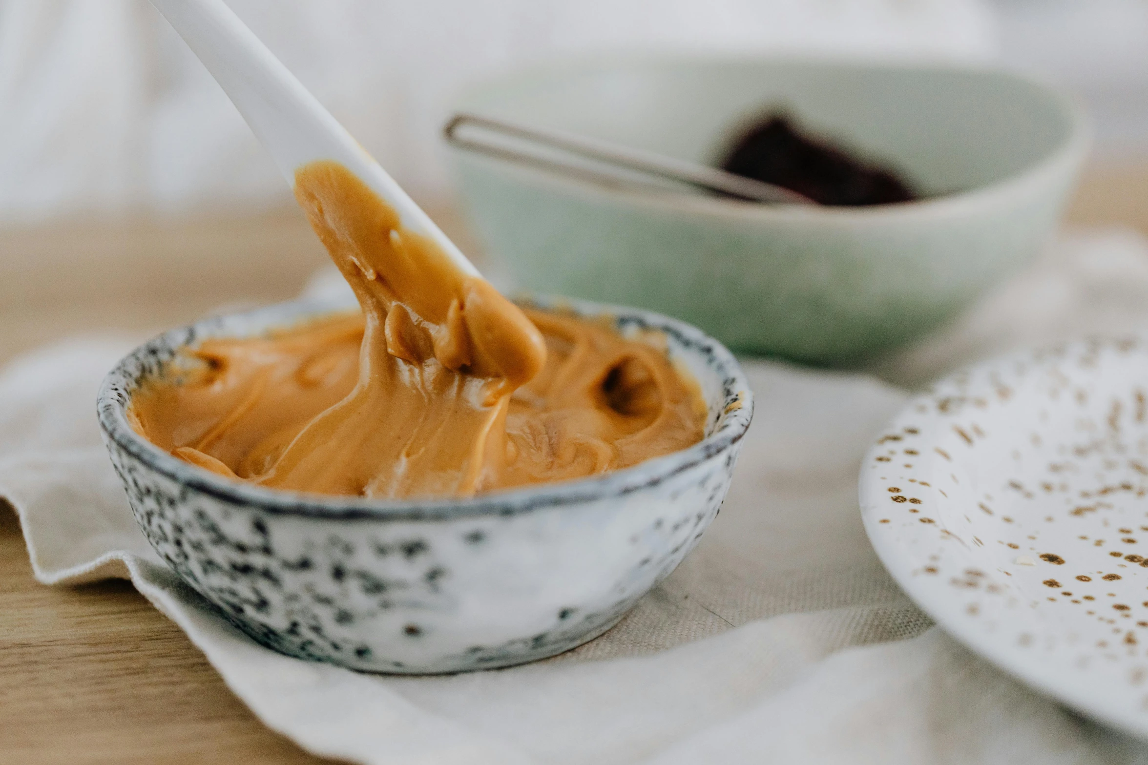 a bowl of peanut butter with a spoon in it, trending on pexels, ochre, glaze, te pae, silk