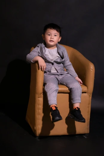 a little boy that is sitting in a chair, inspired by Fei Danxu, pexels contest winner, neo-dada, full body portrait posing, grey clothes, softplay, promotional image