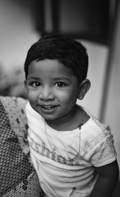 a black and white photo of a little boy, hurufiyya, vinayak, lovingly looking at camera, taken in the late 2010s, portrait of a small character