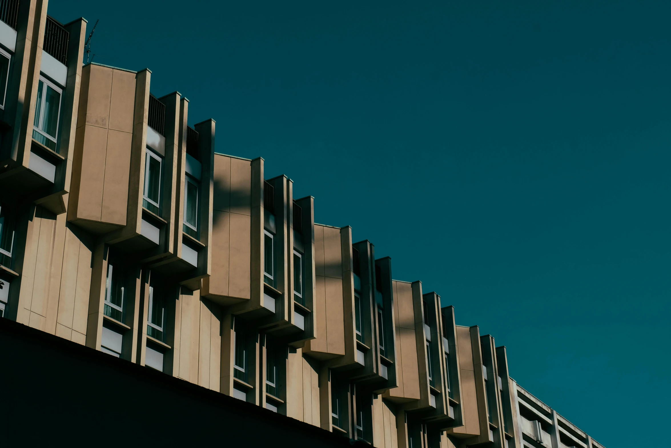 a tall building with many windows in front of a blue sky, unsplash, brutalism, brown, great light and shadows”, copper and deep teal mood, slide show
