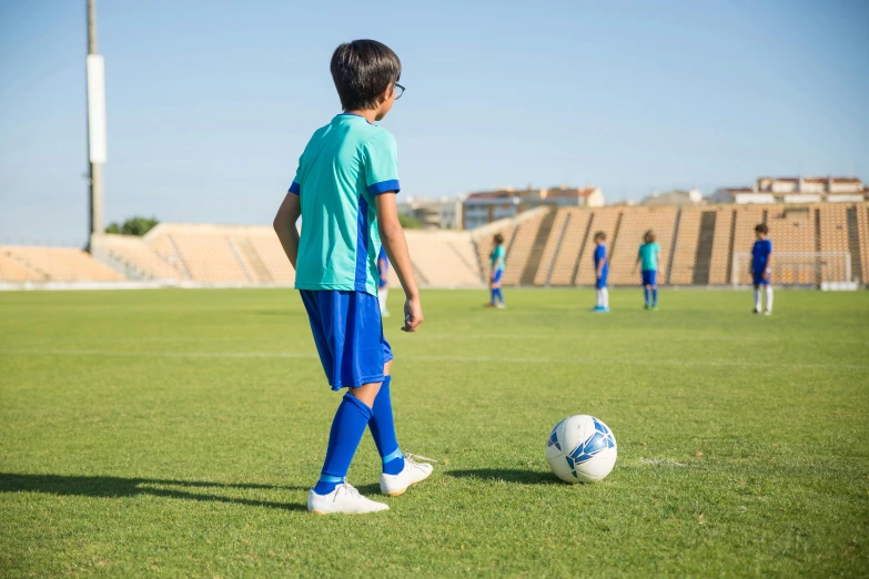 a young boy kicking a soccer ball on a field, trending on dribble, ameera al-taweel, private school, looking onto the horizon, 15081959 21121991 01012000 4k