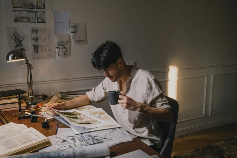 a man sitting at a table with a cup of coffee, a drawing, by Jang Seung-eop, pexels contest winner, process art, studying in a brightly lit room, in his basement studio, promo image, drawing on a parchment