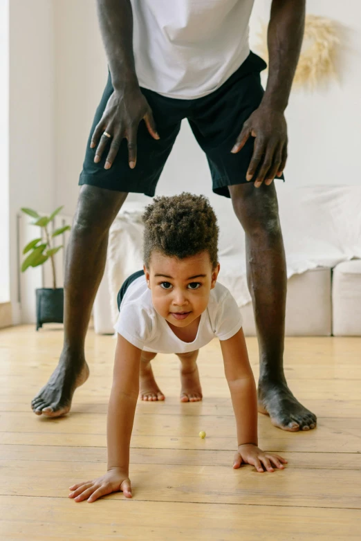 a man standing next to a little boy on a hard wood floor, crawling towards the camera, black man, such as arms & legs, netflix