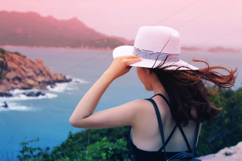 a woman in a hat looking at the ocean, pexels contest winner, pink gradient background, a wanderer on a mountain, wearing a travel hat, summer setting