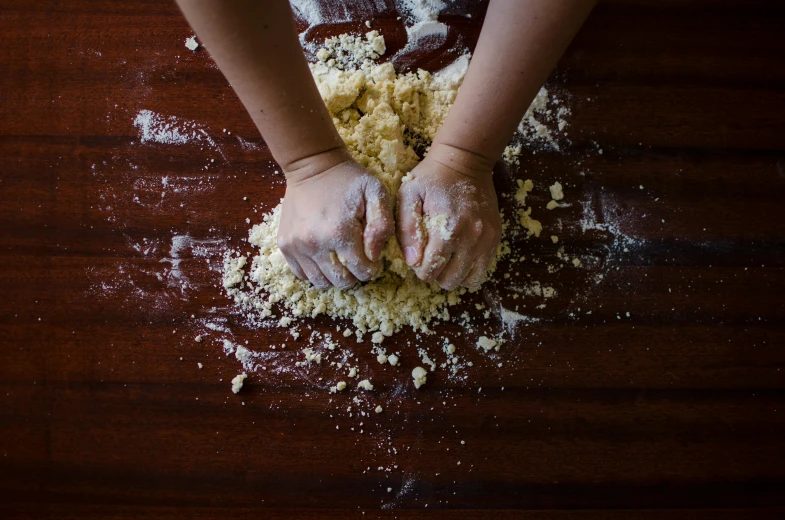 a person that is kning some food on a table, covered in white flour, background image, thumbnail, baking artwork