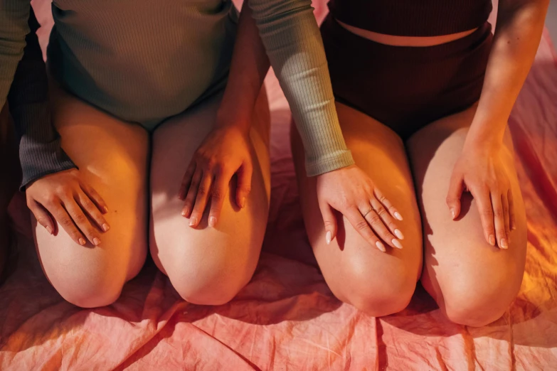 a couple of women sitting on top of a bed, by Ren Hang, trending on pexels, knobbly knees, cysts, ilustration, slightly overweight