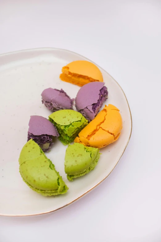 a white plate topped with colorful cookies on top of a table, by Simon Gaon, yellow purple green, bao pnan, macaron, 王琛