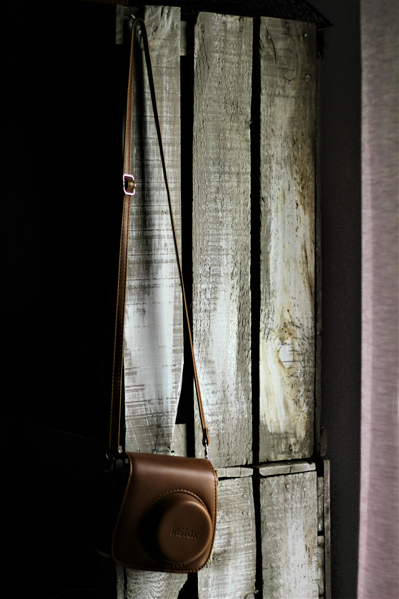 a purse hanging on a wall next to a window, by Peter Churcher, unsplash, studio medium format photograph, rustic, holster, side light