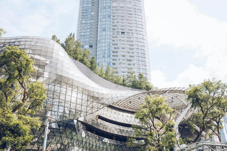 a tall building sitting next to a lush green forest, inspired by Zha Shibiao, unsplash contest winner, hypermodernism, bangkok townsquare, with shiny glass buildings, sustainable materials, on a futuristic shopping mall