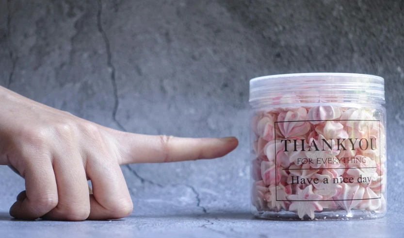 a person pointing at a jar of marshmallows, trending on pexels, visual art, pink petals fly, in style of thawan duchanee, thedieline, thin face