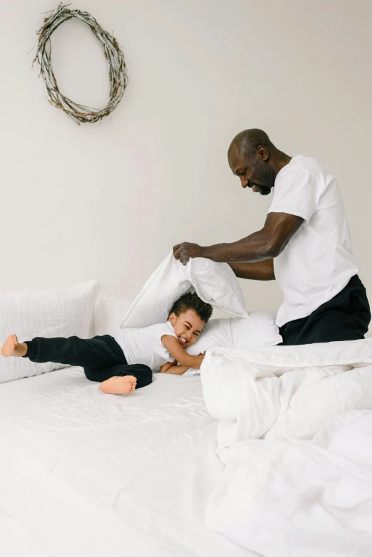 a man and a woman laying on a bed, father with child, thumbnail, throw pillows, standing still