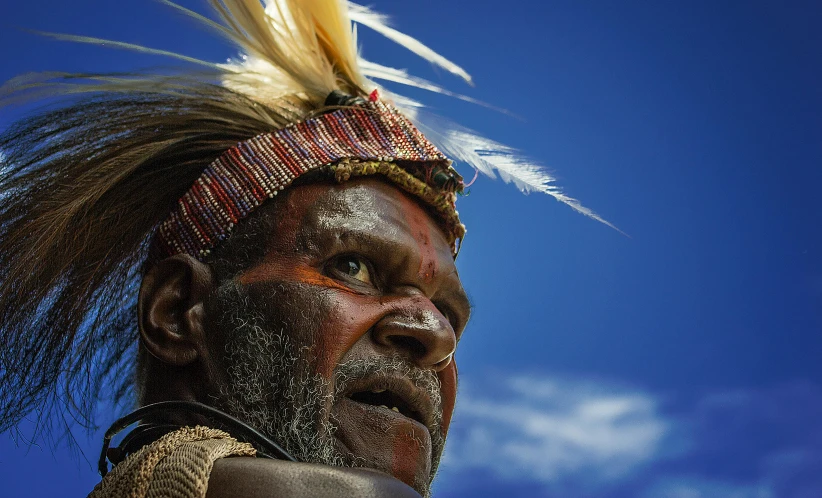 a close up of a person wearing a headdress, by Peter Churcher, hurufiyya, blue sky, national geography photography, old male, deep colours. ”