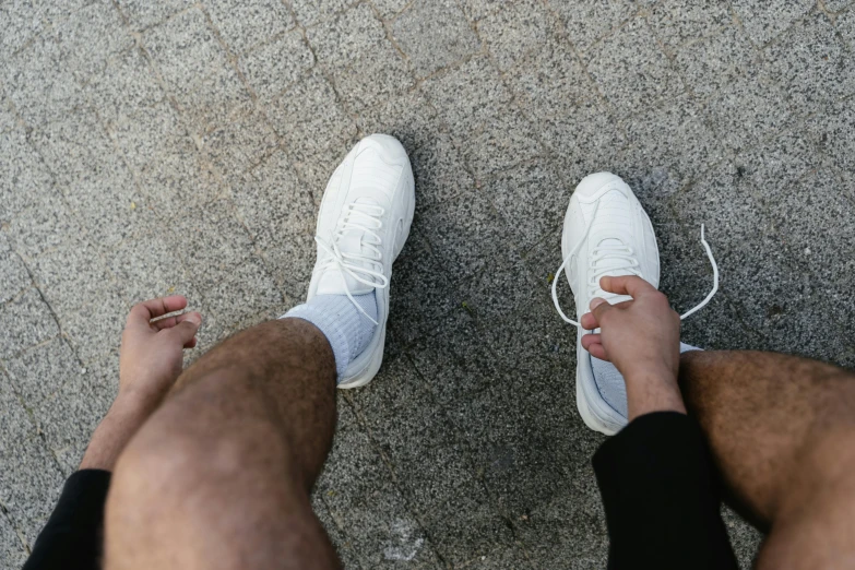 a man wearing a pair of white tennis shoes, by Adam Marczyński, pexels contest winner, renaissance, chalk white skin, hairy legs, different sizes, ignant