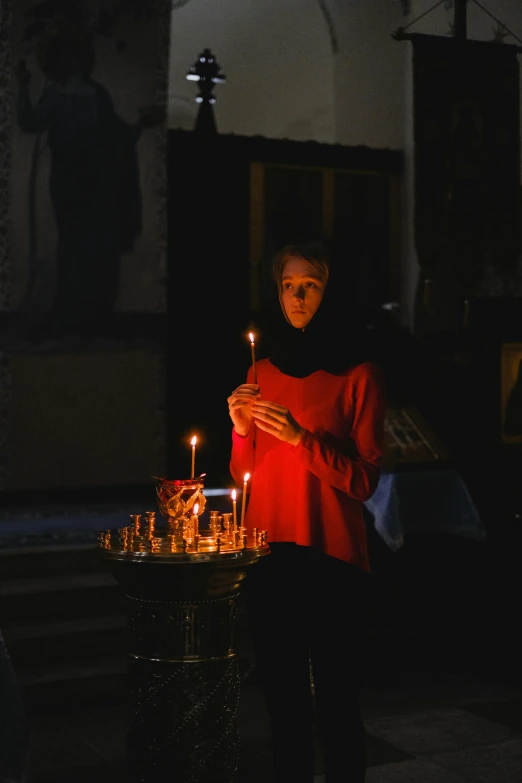 a woman holding a lit candle in a church, by Julia Pishtar, pexels, middle eastern, a seance, instagram post, ukrainian monk