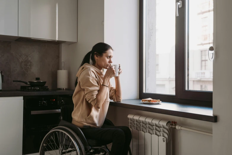 a woman in a wheelchair looking out a window, trending on pexels, hurufiyya, over a dish and over a table, muscular and exhausted woman, profile image, table in front with a cup