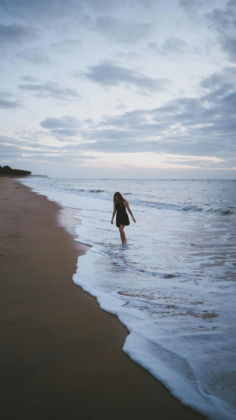 a woman standing on top of a beach next to the ocean, by Jessie Algie, unsplash contest winner, walking on water, teenage girl, calm evening, australian beach
