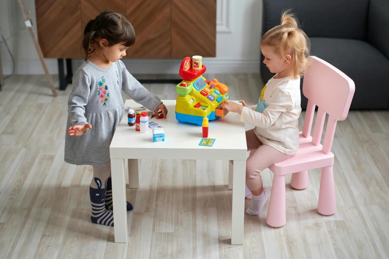 two little girls sitting at a table playing with toys, a picture, cash register, casual playrix games, tables and chairs, product view