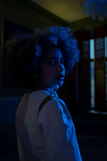 a woman with curly hair standing in a dark room, dramatic white and blue lighting, her hair is white, young black woman, with glowing windows