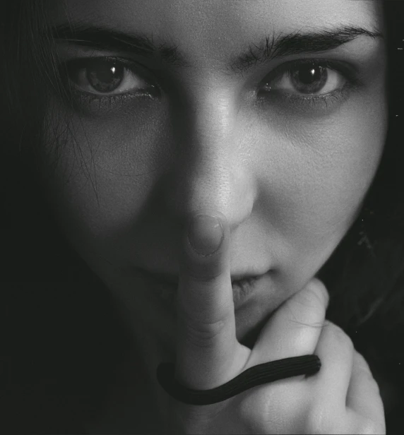 a black and white photo of a woman with a finger on her lips, by Adam Marczyński, pexels contest winner, censored, stealth, close-up!!!!!, brunette woman