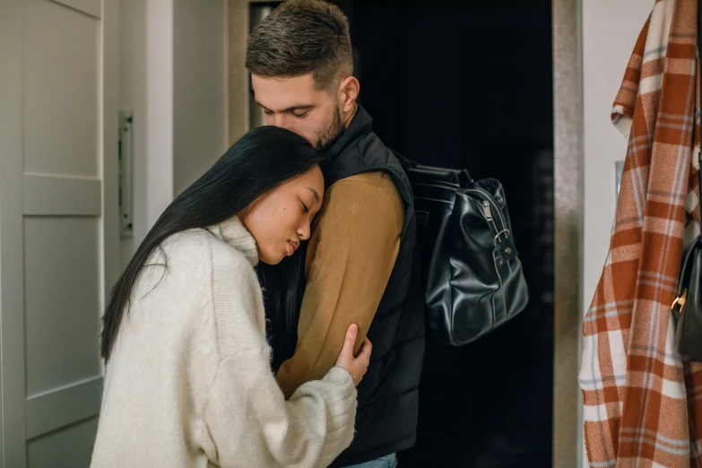 a man and woman hugging each other in a hallway, pexels contest winner, happening, bag over the waist, mourning family, an asian woman, winter