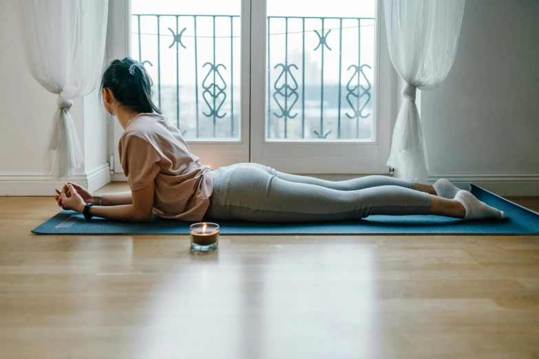 a woman sitting on a yoga mat in front of a window, a picture, trending on pexels, arabesque, face down, woman is curved, panoramic shot, sydney hanson