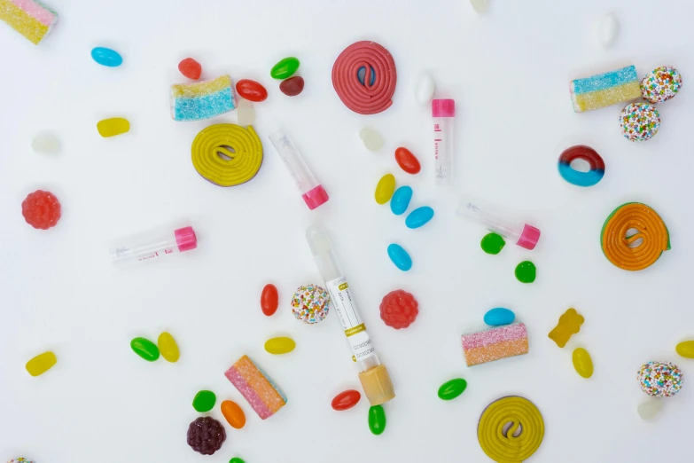 a white table topped with lots of different types of candies, inspired by Damien Hirst, pexels, holding a syringe, background image, product shot, karim rashid