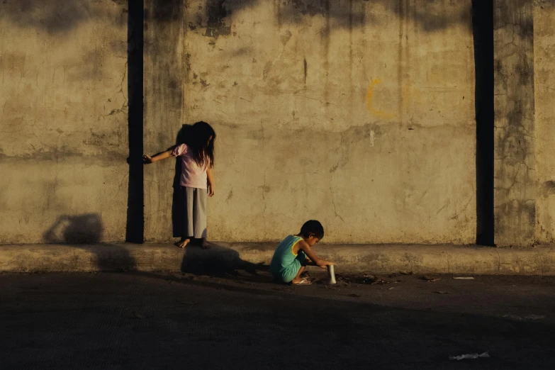 a couple of young girls standing next to a cement wall, by Elsa Bleda, unsplash contest winner, manila, families playing, late afternoon sun, in a square