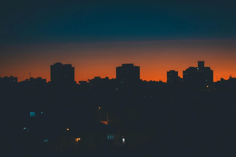 a view of a city at night from the top of a hill, an album cover, inspired by Elsa Bleda, pexels contest winner, orange and blue sky, minimalistic aesthetics, silhouetted, humid evening