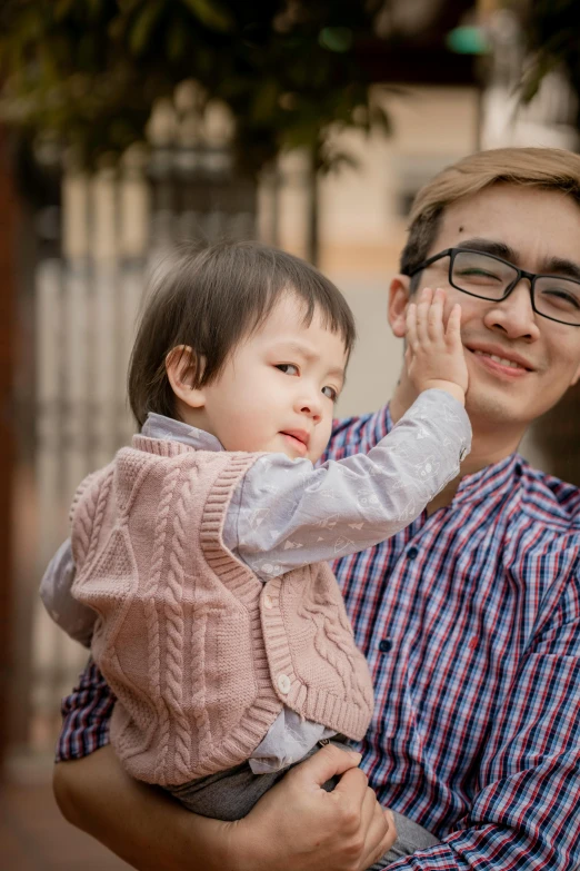 a man holding a small child in his arms, a picture, inspired by Yeong-Hao Han, pexels contest winner, waving at the camera, playful smirk, highly detailded, lightly dressed