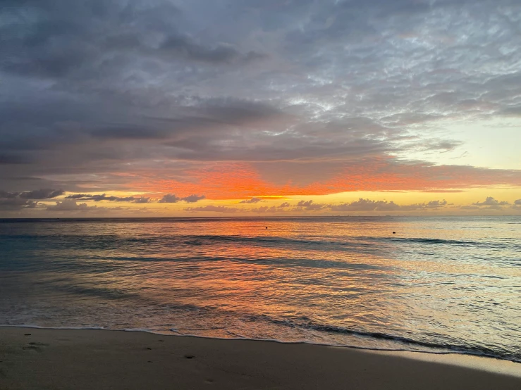 a large body of water sitting on top of a sandy beach, by Carey Morris, pexels contest winner, sunrise colors, varadero beach, overcast skies, photo of the middle of the ocean