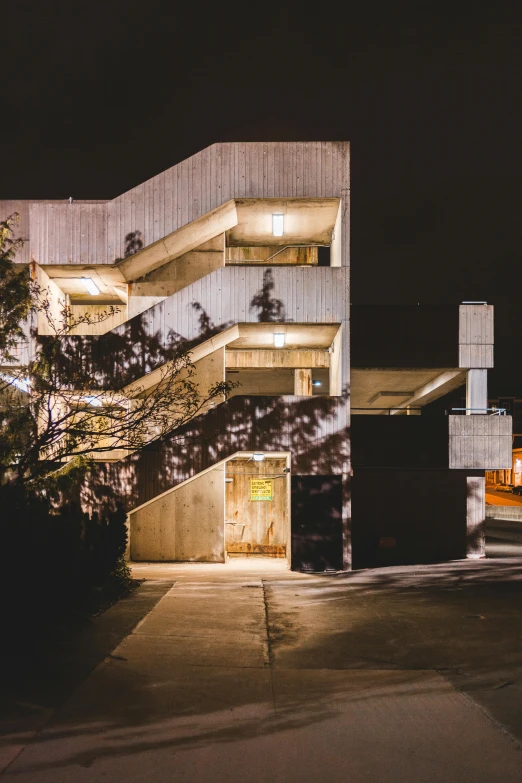 a car parked in front of a building at night, inspired by Ned M. Seidler, unsplash, brutalism, outdoor staircase, schools, 1980s photograph, high-resolution photo