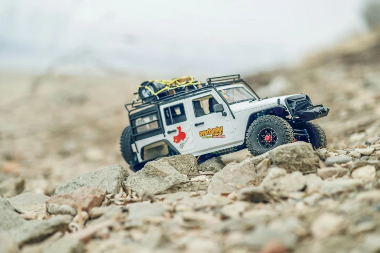 a toy jeep sitting on top of a pile of rocks, a tilt shift photo, by Sebastian Spreng, unsplash, climbing up a cliffside, 1/6 garage resin kit, “erebos’s titan, with a roof rack